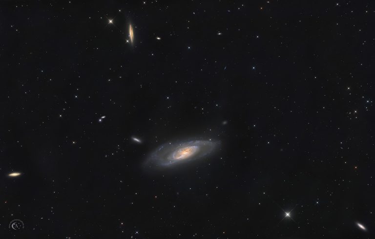 Weitfeld-Astrofotografie von M106 und der kantenständigen Hintergrundgalaxie NGC 4217 mit zahlreichen weiteren kleinen Galaxien im Sternbild Jagdhunde.