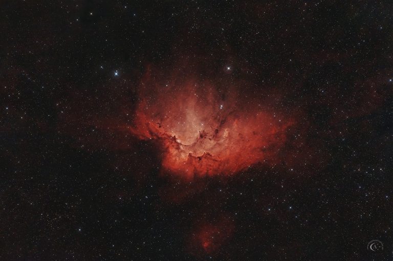 Aufnahme des Wizardnebels Sh 2-142 mit dem jungen Sternhaufen NGC 7380 inmitten gegliederter heller und dunkler Nebelstrukturen.